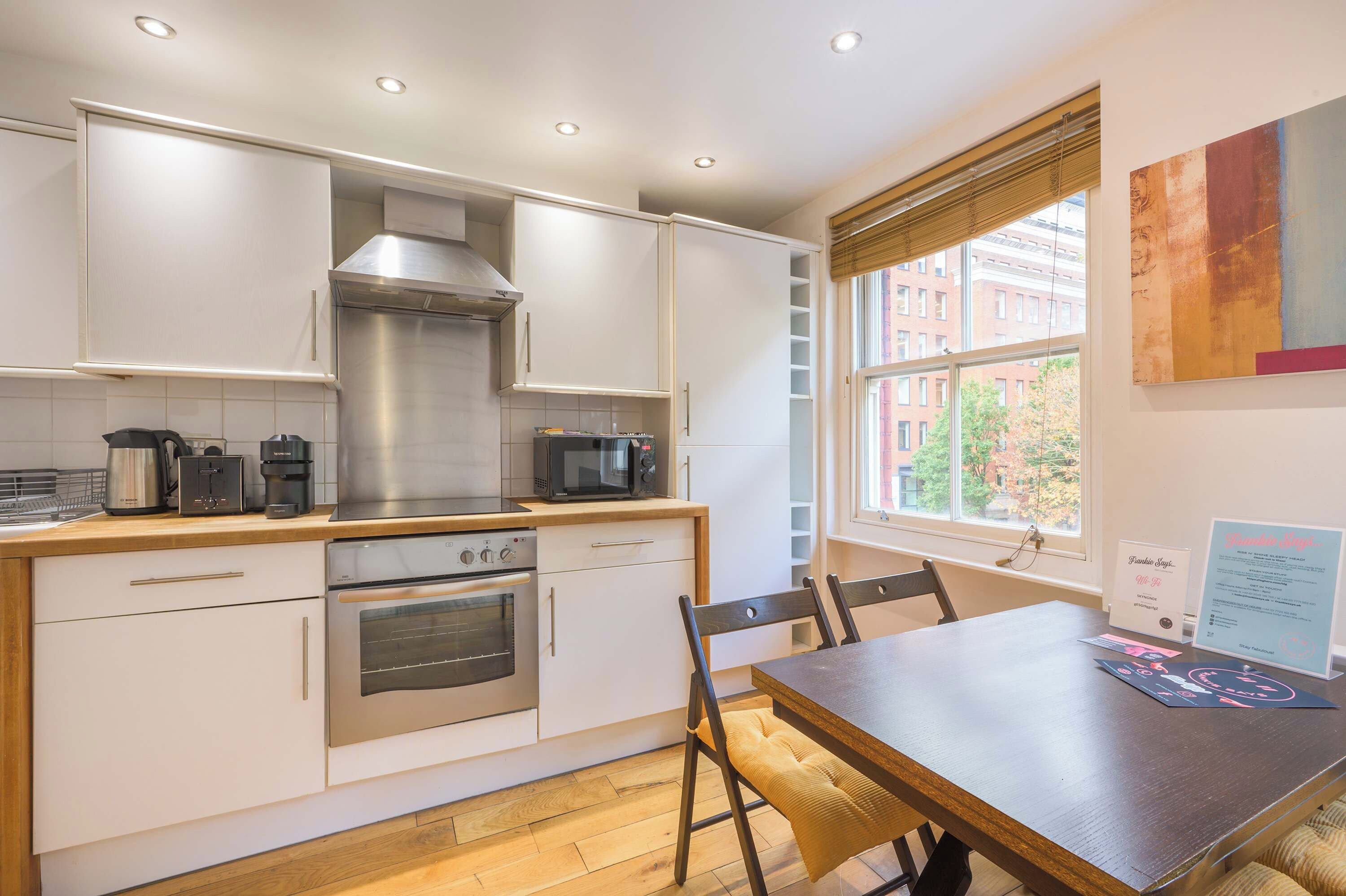 Una cocina moderna con armarios blancos, electrodomésticos de acero inoxidable y una mesa de comedor de madera.