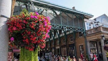 A bustling market with a prominent hanging flower display and traditional architecture.
