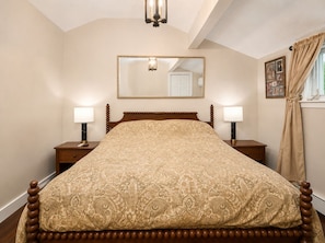 A bedroom with a bed, two bedside tables, a nightstand, a mirror, a window with curtains, and a chandelier. - Riverside Cottage • Fireplace • Mountain Views (Bartlett)