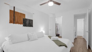 Une chambre d’hôtel moderne avec un grand lit, un ventilateur de plafond et un rideau fixé au mur.