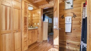 Innenansicht einer Holzhütte mit Küchenbereich, Holzschränken und einer Tür zu einem anderen Raum.