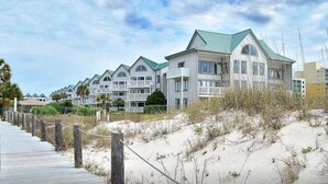 Ein Strandhotel mit mehreren Gebäuden, einer Promenade und Sanddünen.