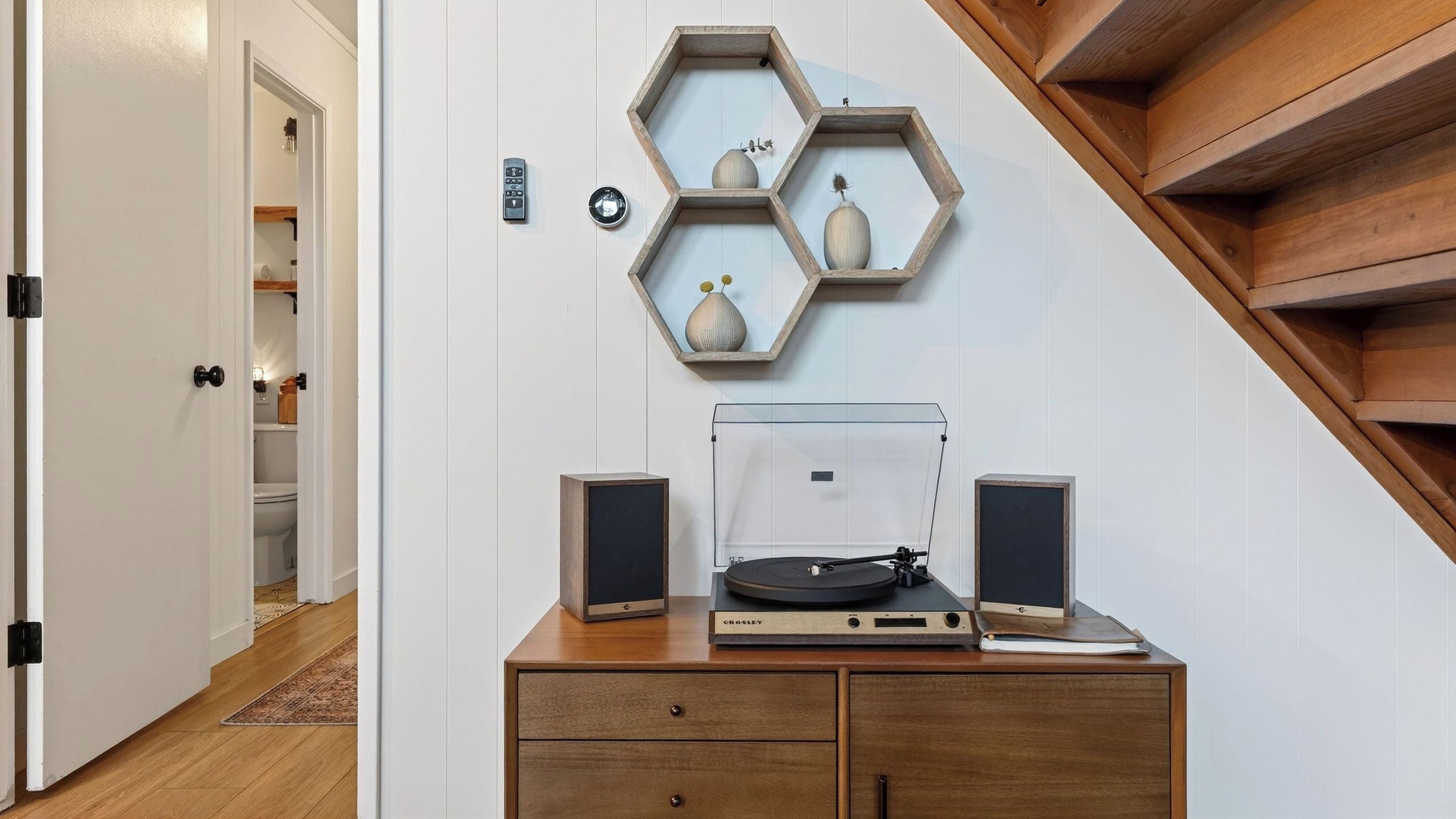 A room with a wooden cabinet, a turntable, speakers, and hexagonal shelves with decorative items.