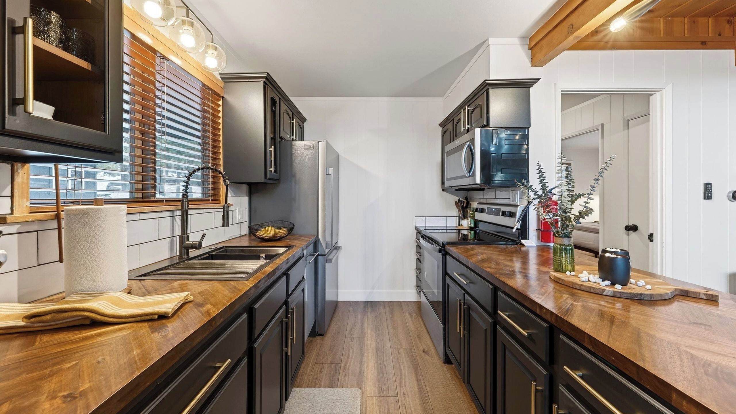 Een moderne keuken met een centraal eiland, houten werkbladen en inbouwapparatuur.