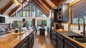 A spacious kitchen with high ceilings, large windows, and a central island. - Hot Tub Firepit Loft Suite & Mins to World-class Skiing Tahoe A-frame Retreat by Avantstay (Carnelian Bay)