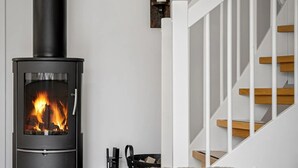 A modern living room with a wood-burning stove, a staircase, and a cozy seating area.