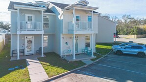 Um edifício residencial de dois andares com varanda frontal, garagem e estacionamento.