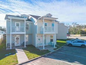 A two-story residential building with a front porch, a garage, and a parking lot. - Two King Suites - POOL - Short Walk to the Beach (Gulfport)