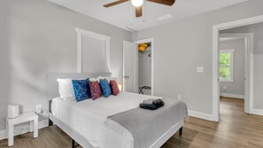 A bedroom with a bed, bedside tables, a ceiling fan, and a walk-in closet. - Tranquil 3-bedroom house in charming Decatur   Near Attractions! (Decatur)