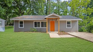 A small, single-story house with a grey siding exterior, a brown door, and a small front porch. - Tranquil 3-bedroom house in charming Decatur   Near Attractions! (Decatur)