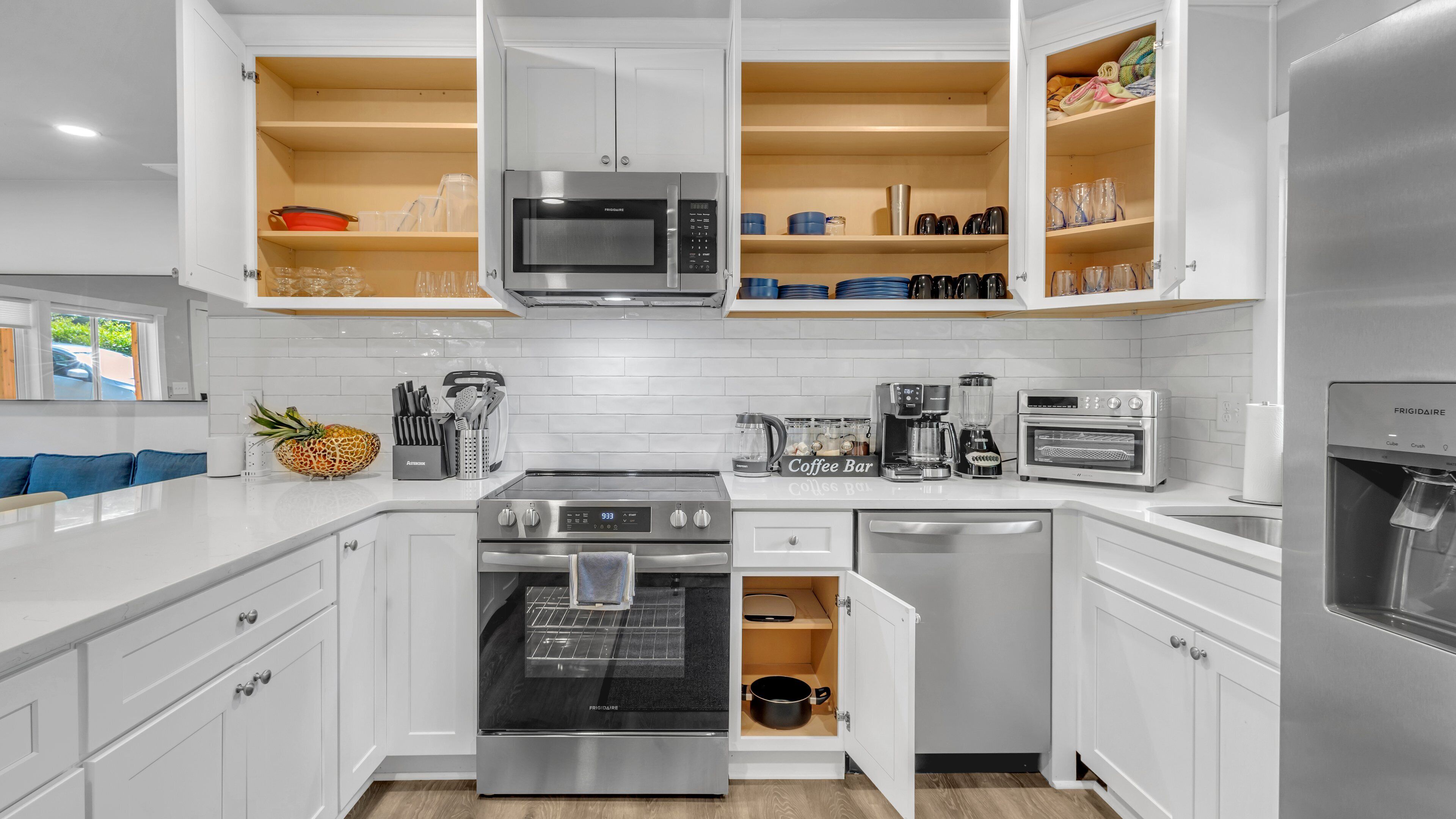 A modern kitchen with white cabinetry, stainless steel appliances, and a built-in oven.
