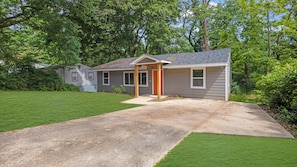 Une maison d’habitation avec un porche à l’avant, une allée et une pelouse bien entretenue.