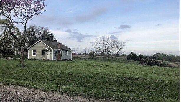 Ett envåningshus med ett sadeltak, en veranda och en liten trädgård framför huset.