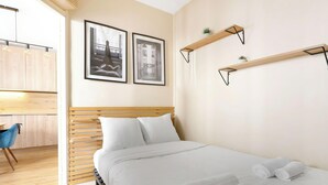 A modern bedroom with a wooden bed, white bedding, two framed pictures, and a small shelf with plants. - Luminous apartement 1BDR/4P - Centre de Paris (Paris)