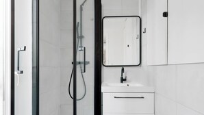 A modern bathroom with a glass shower enclosure, a white sink, and a mirror above it. - Luminous apartement 1BDR/4P - Centre de Paris (Paris)