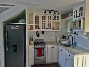 A compact kitchen with white cabinets, a stainless steel refrigerator, a stove, and a sink. - The Ultimate escape on beautiful Mahogany Beach, Ocho Rios (Ocho Rios)