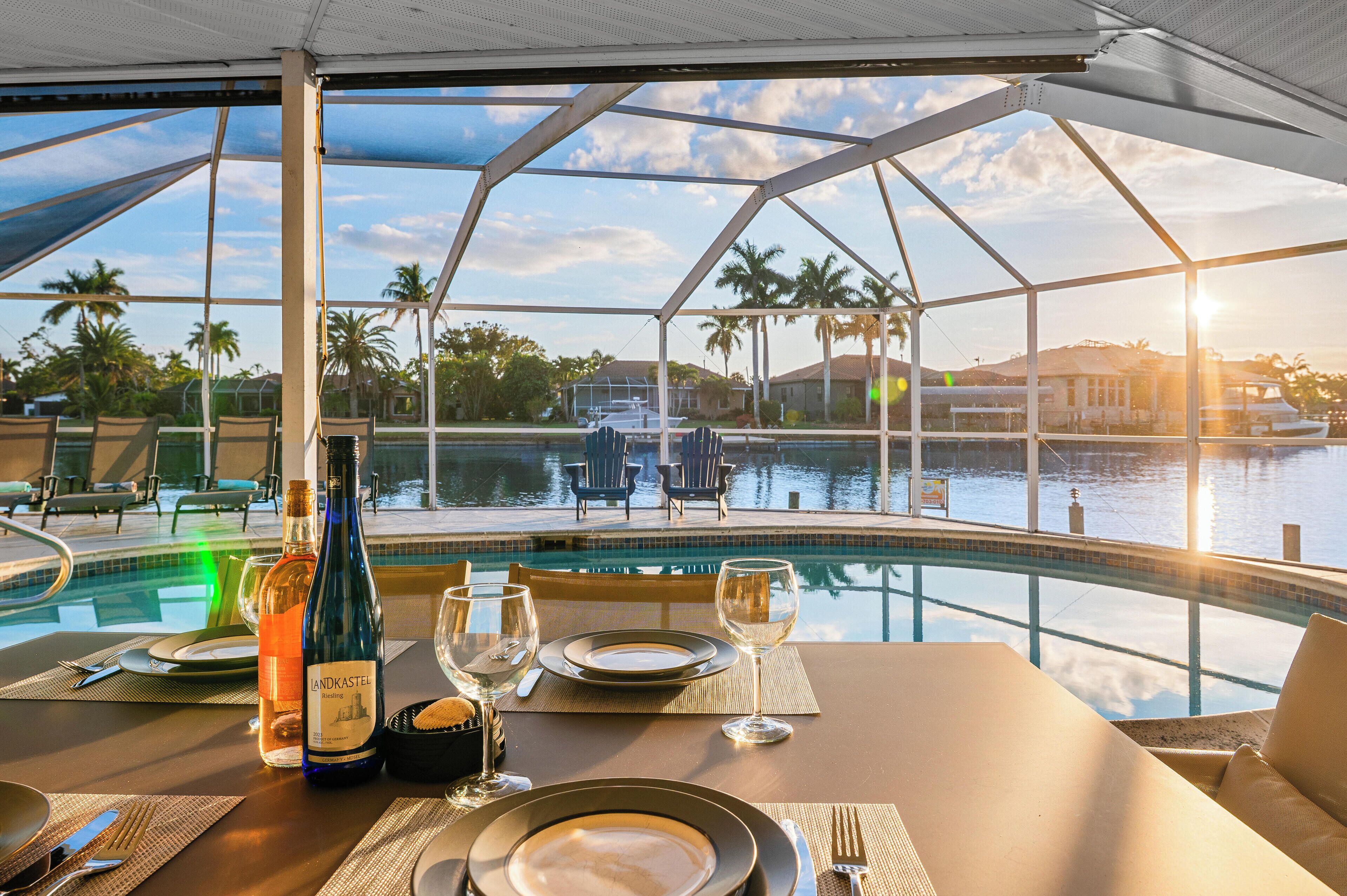 A dining area with a view of a swimming pool and palm trees.