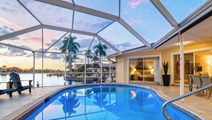 Una piscina interior con vistas a un puerto deportivo y palmeras.