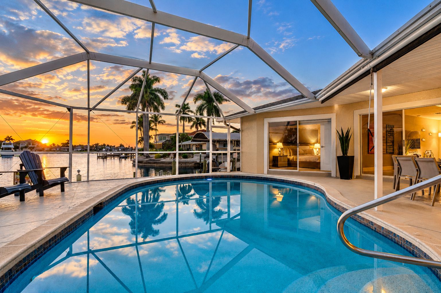 A swimming pool with a glass ceiling, a sunset view, and a dining area with chairs.