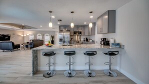Una cocina moderna con una isla de mármol, taburetes de bar y electrodomésticos de acero inoxidable.