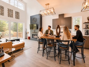 Une cuisine moderne avec une grande table à manger, une cheminée et un téléviseur fixé au mur.