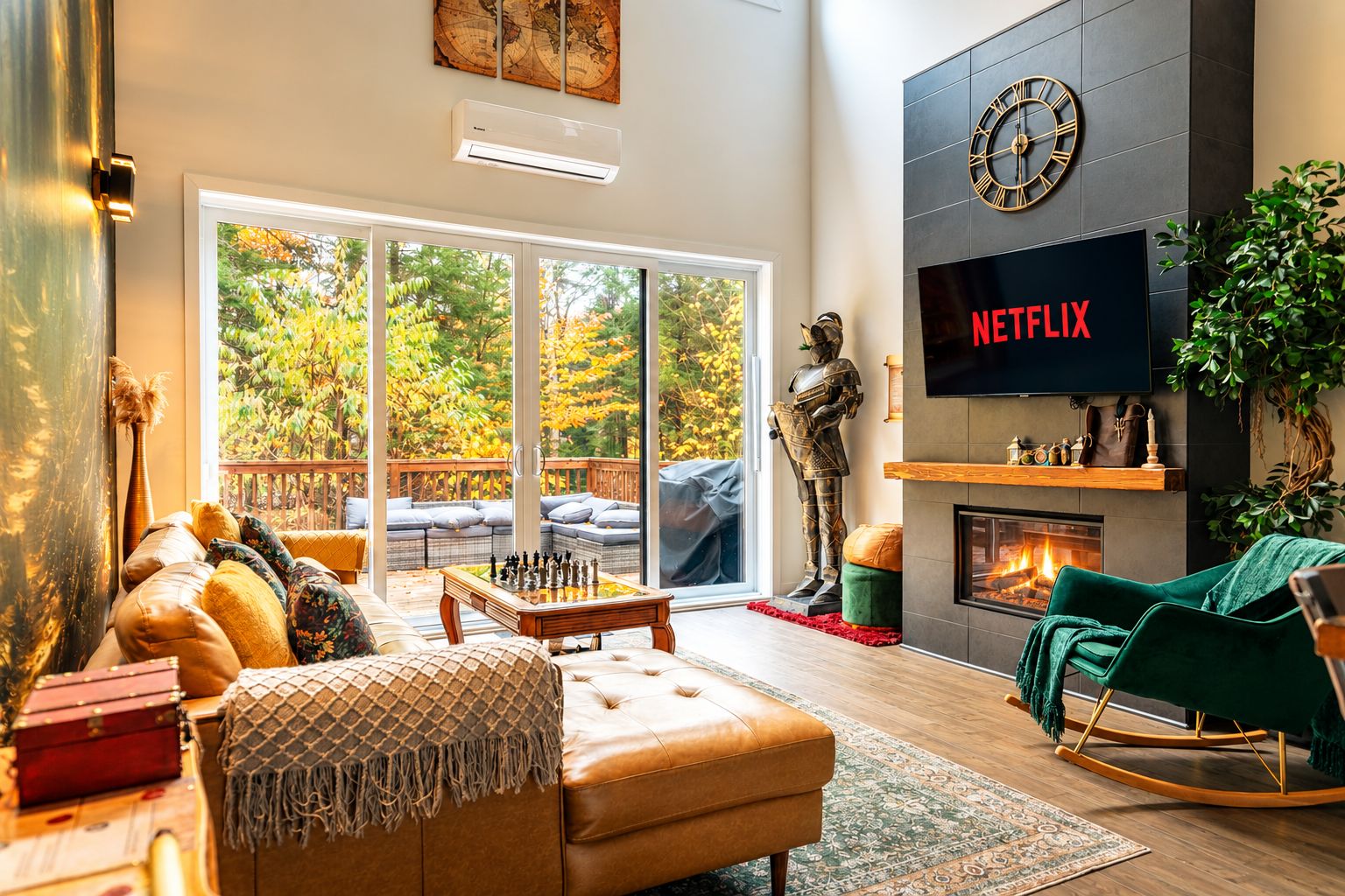 A modern living room with a fireplace, a large TV screen displaying 'NETFLIX', and a view of autumn foliage through the glass doors.