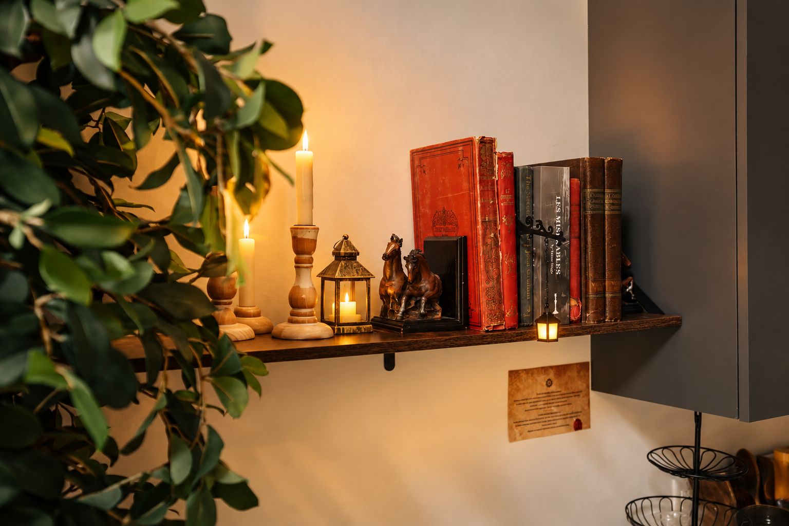 A shelf with books, candles, and a lantern.