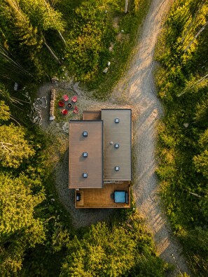 Vue aérienne d’un chalet doté d’une terrasse en bois, d’un bain à remous et d’un foyer extérieur.
