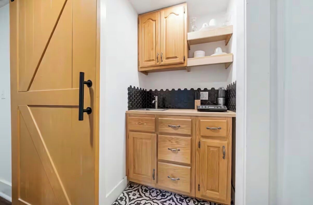 A compact kitchen with wooden cabinets, a black countertop, and a tiled backsplash.