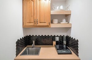 Eine Küche mit Holzschränken, einer schwarzen, sechseckigen Spritzschutzwand, einer Edelstahlspüle und einem schwarzen Induktionskochfeld.
