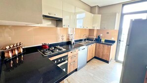 Una cocina moderna con encimera negra, electrodomésticos de acero inoxidable y armarios de madera.