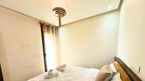 Habitación de hotel con cama, lámpara en el techo y puerta con cortina.