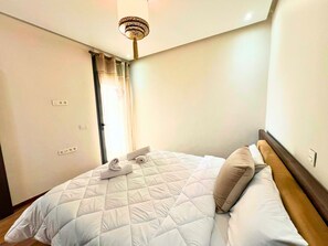 Ein Hotelzimmer mit Bett, Deckenleuchte und einer Tür mit Vorhang.