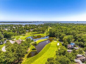 A golf course with a water hazard, surrounded by residential areas and a body of water in the background. - Ocean Pines Getaway with Beach Pass (Ocean Pines)