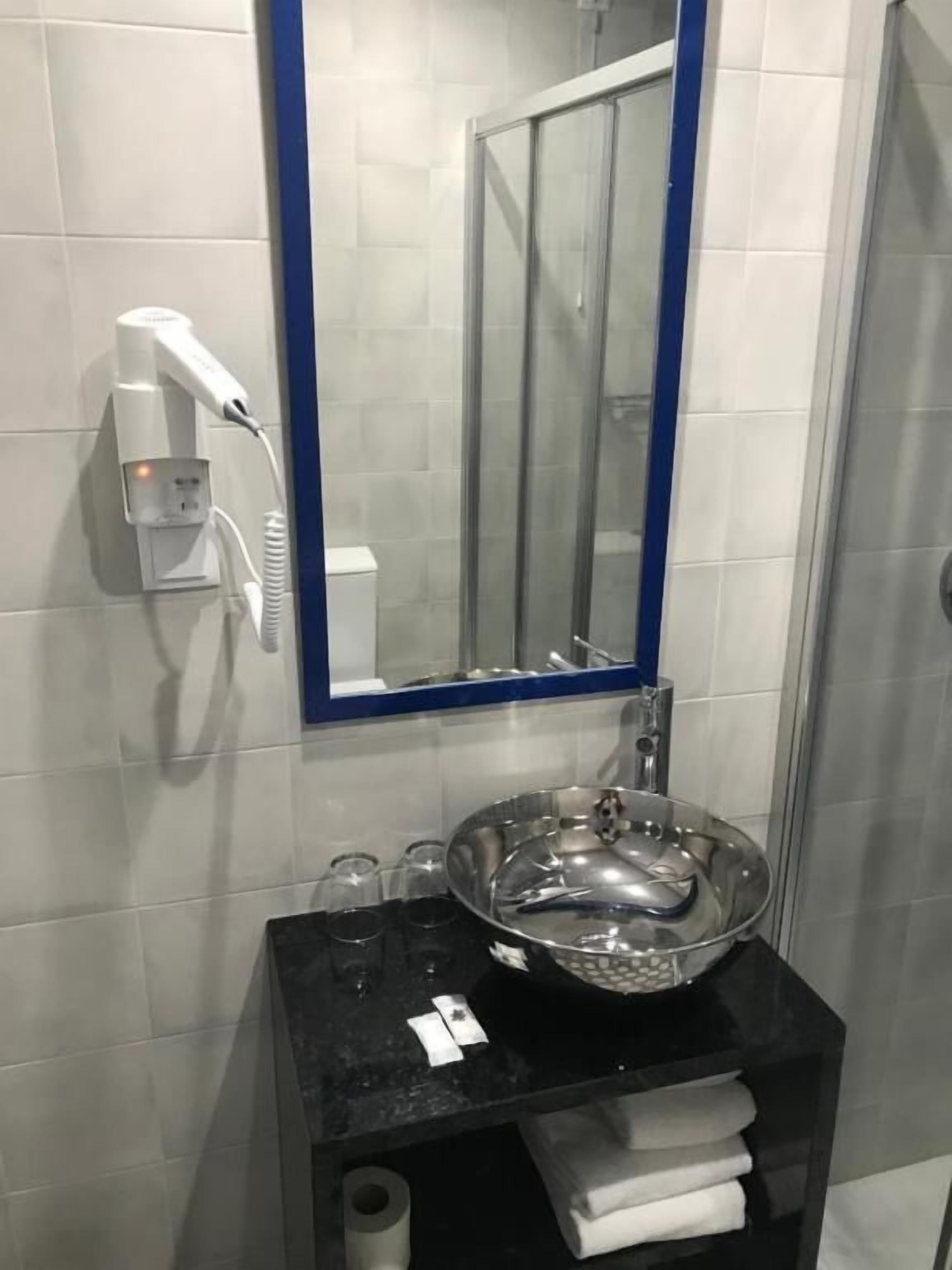 A bathroom with a sink, mirror, and hairdryer.