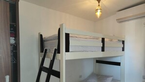 Ein Stockbett mit einer Leiter, ein Nachttisch und eine an der Wand befestigte Lampe.