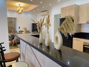 A modern kitchen with a black countertop, wooden cabinets, and decorative vases with pampas grass. - Selena bay resort villa 5 BR in Hurghada (Hurghada)