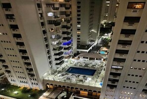 A high-rise building with multiple balconies, a rooftop pool area, and a courtyard with outdoor seating. - Apartment in the best location in Pitangueiras, Guarujá, pets allowed. (Guarujá)