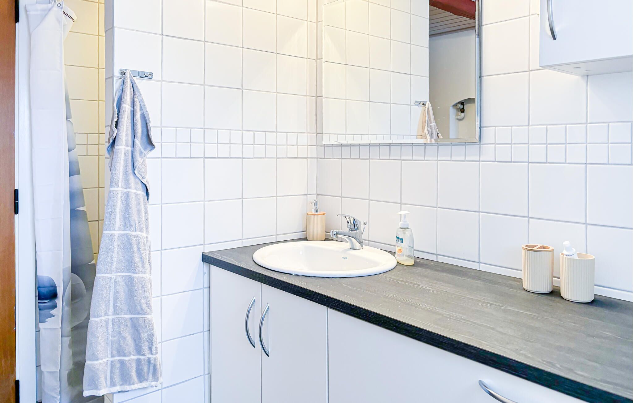 Ein Badezimmer mit einem weißen Waschbecken, einem Spiegel und einer Duschvorhang.