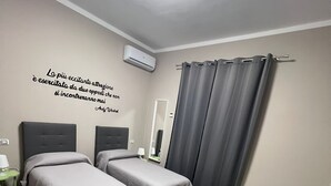 Een hotelkamer met twee bedden, een klein tafeltje, een stoel, een spiegel en een muisbriefje.