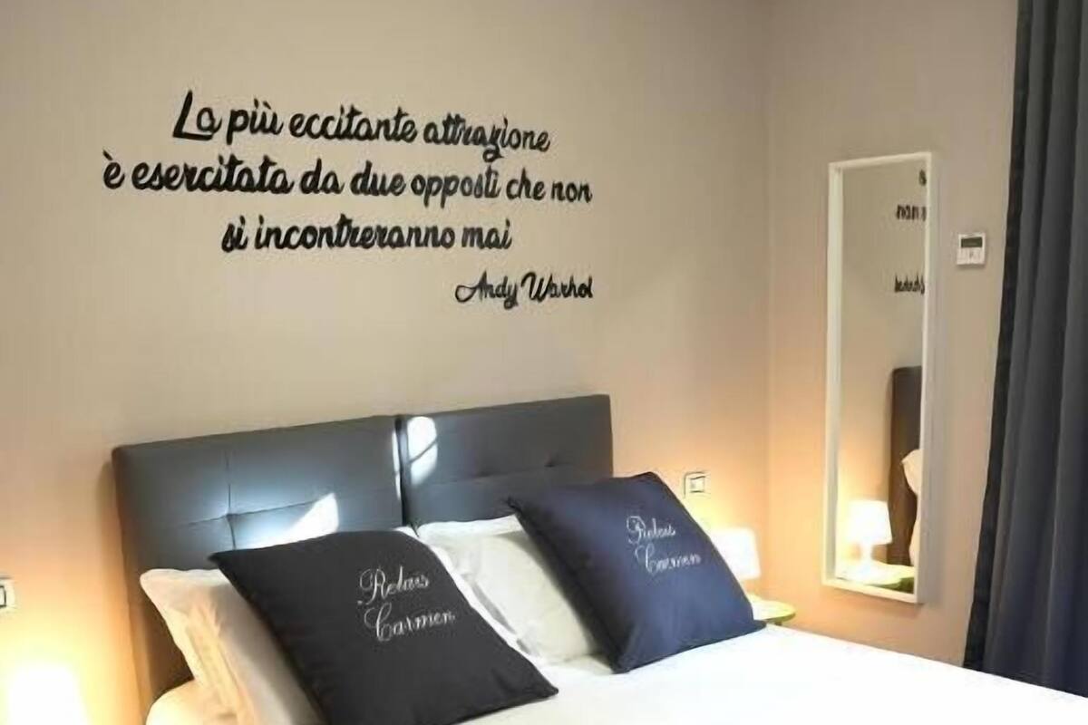 Un lit bien fait avec deux oreillers, une table de chevet avec une lampe et un climatiseur fixé au mur.