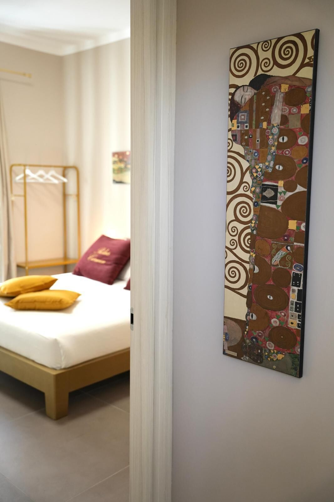 A bedroom with a bed, a wall-mounted artwork, and a window with curtains.