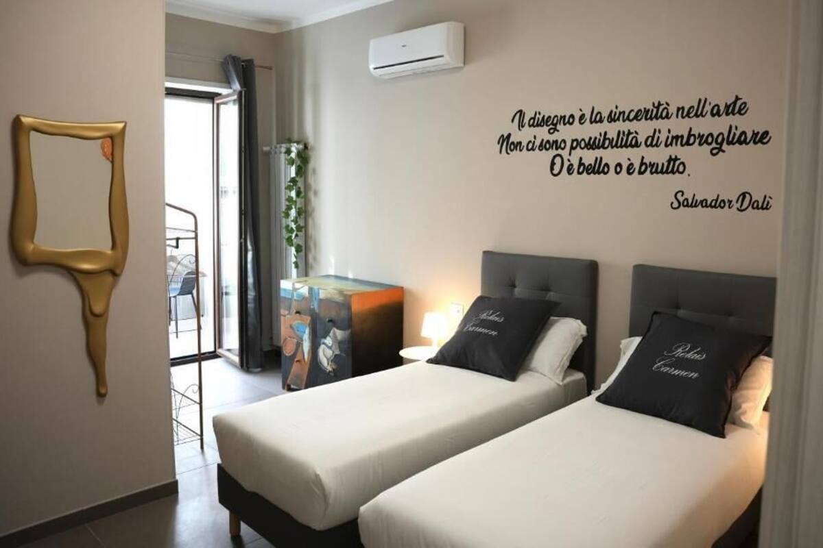 Une chambre d’hôtel avec deux lits, une citation affichée sur le mur et une fenêtre.