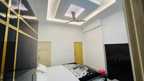 A modern bedroom with a bed, a ceiling fan, and a wardrobe. - Hotel Vallabh Palace (Misrikh)