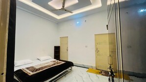 A bedroom with a bed, a ceiling fan, and two doors. - Hotel Vallabh Palace (Misrikh)