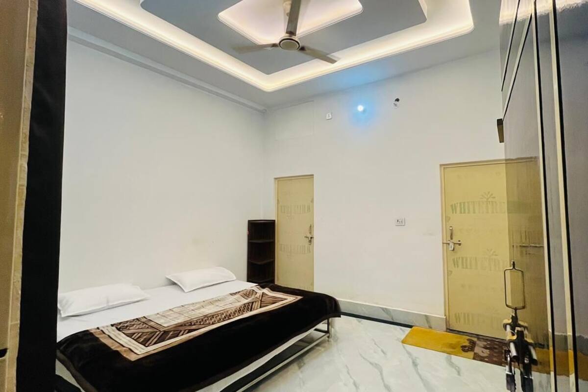 Une chambre à coucher avec un lit, un ventilateur de plafond et deux portes.
