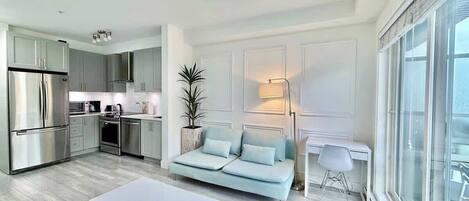 Una cocina moderna con electrodomésticos de acero inoxidable, un comedor con mesa blanca y un sofá azul claro.