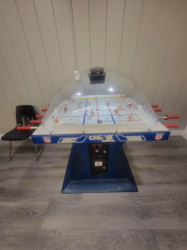 A foosball table with a transparent dome, surrounded by chairs, in a room with wooden flooring. - Cedar Lodge Condo w/ Loft and private balcony (Laconia)