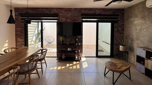 Un soggiorno moderno con una parete in mattoni, un tavolo da pranzo in legno e una ventola a soffitto.