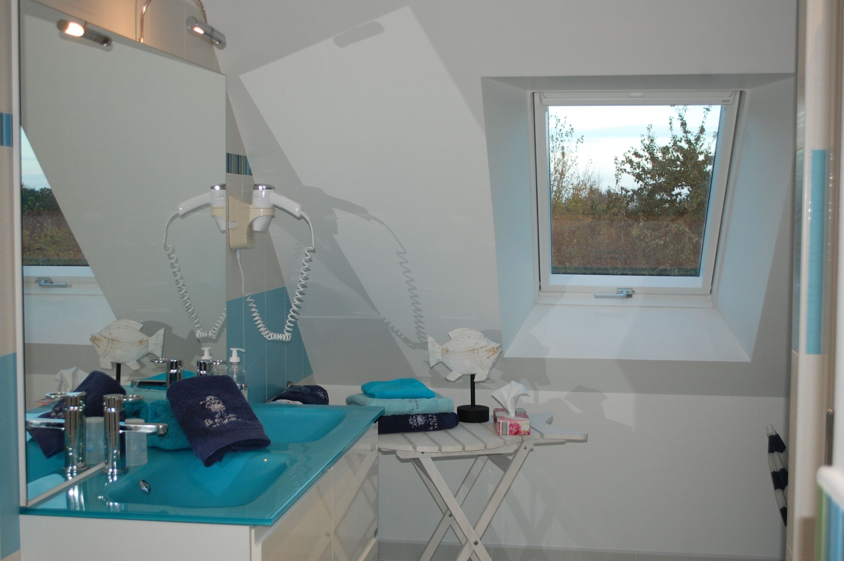 A bathroom with a large mirror, a window, and a sink with toiletries.